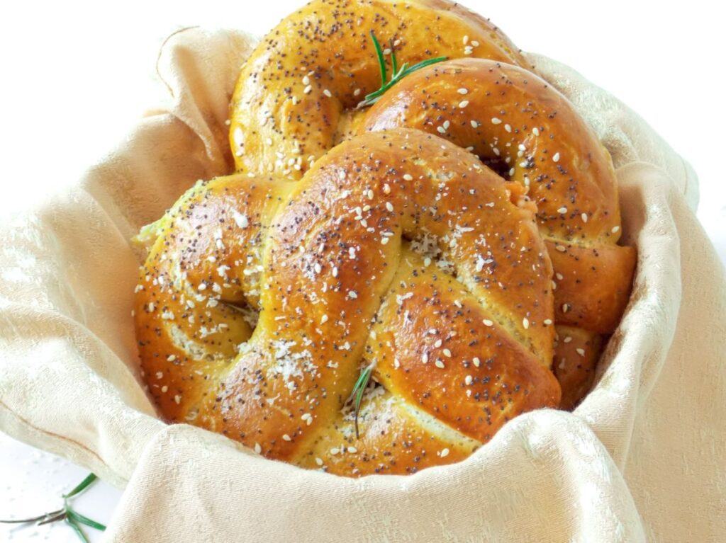 Covrigi umpluți cu brânză, rumeni și pufoși, așezați într-un coșuleț rustic, perfect copți și aurii.