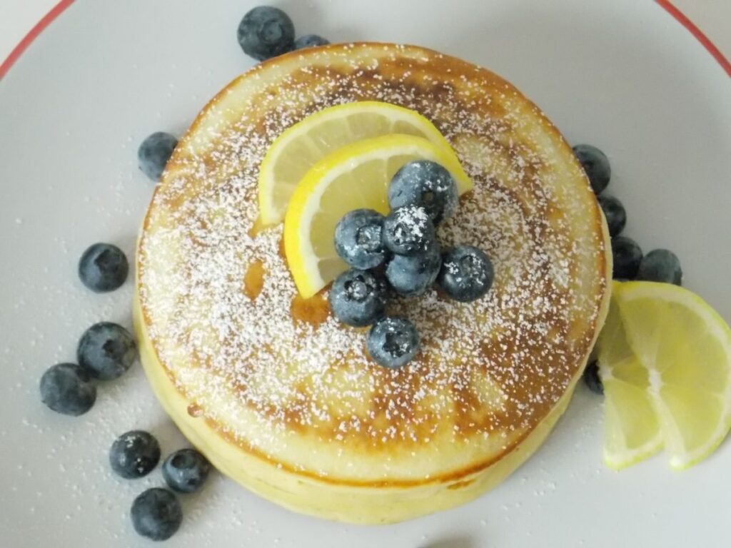 Pancakes clatite americane pufoase, decorate cu zahar pudra, afine si lamaie