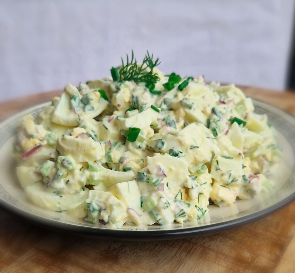 Salată de ouă cremoasă, cu țelină apio, ceapă roșie, mărar și un strop de maioneză, servită ca aperitiv sau masă ușoară.