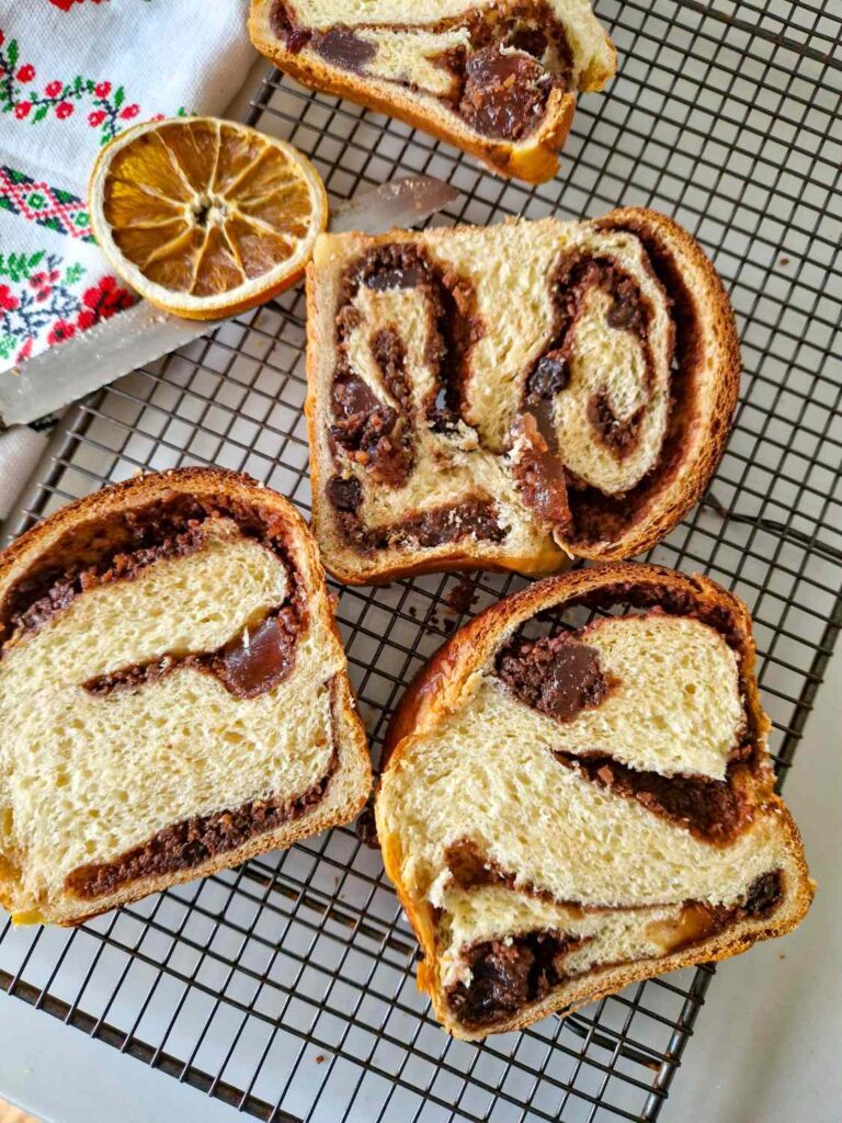 Cozonac pufos cu smântână proaspăt scos din cuptor, feliat unde se vede umplutura bogata si textura pufoasa si frageda