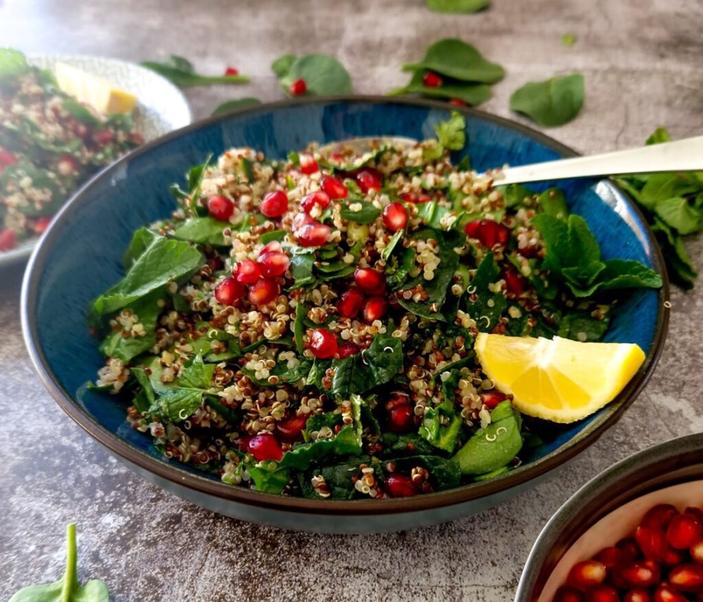Un bol generos de salata viu colorata din spanac, quinoa, rodie, cu menta si lamaie, ideală pentru o masă sănătoasă de vară.