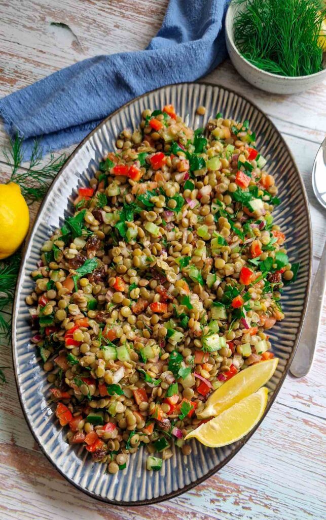 Salată de linte verde cu legume proaspete, inclusiv roșii, castraveți și ardei gras, servită într-un platou mare , perfectă pentru o masă răcoritoare de vară