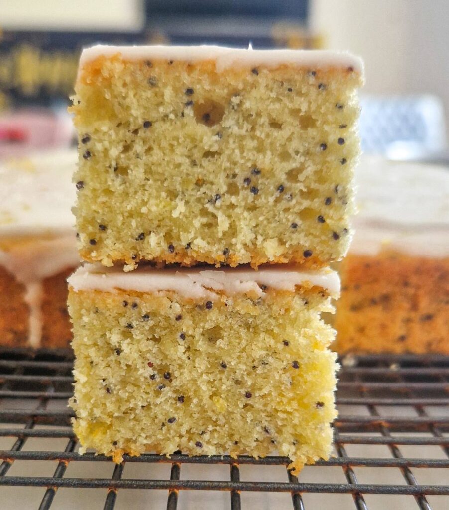 Doua bucati de prajitura cu mac si lamaie una peste cealalta unde se evidentiaza cat de pufoasa si frageda este 