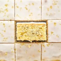 Prajitura cu lamaie si mac cu glazura de zahar portionata in bucati egale unde se vede textura si culoarea minunatat al acestei prajituri