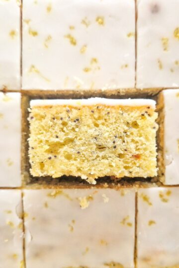 Prajitura cu lamaie si mac cu glazura de zahar portionata in bucati egale unde se vede textura si culoarea minunatat al acestei prajituri