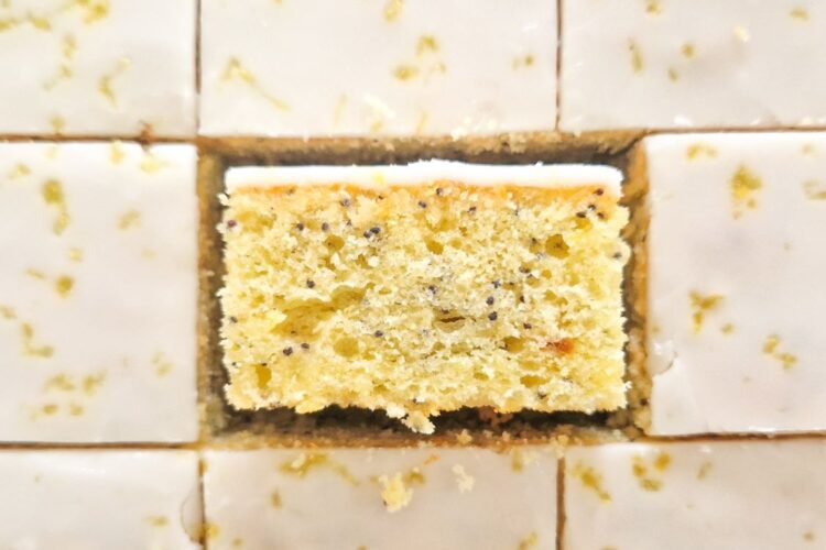 Prajitura cu lamaie si mac cu glazura de zahar portionata in bucati egale unde se vede textura si culoarea minunatat al acestei prajituri