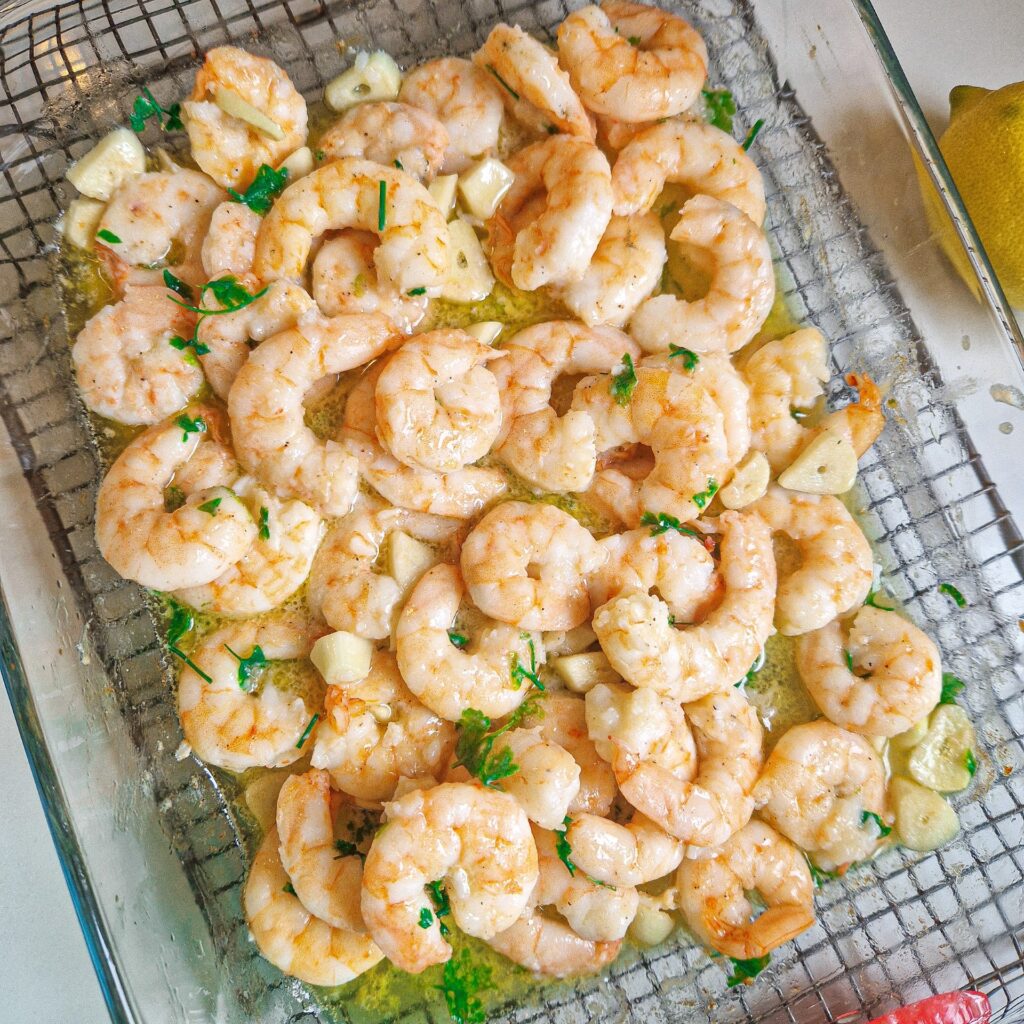 Creveți la cuptor, pregătiți cu unt topit, usturoi aromat și pătrunjel verde proaspăt, o rețetă rapidă și delicioasă.