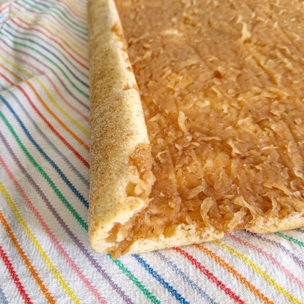 Blatul copt al ruladei cu mere, cu hârtia de copt care este dezlipită.