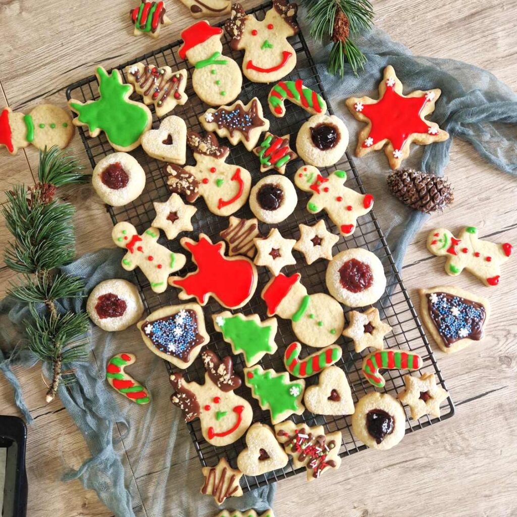 O selectie de biscuiti festivi pentru craciun , in forma sw mosi de zapada, braduti, stele, colorati si decorati cu glazura de zahar rosie si verde, unii umpluti cu dulceata altii cu ciocolata