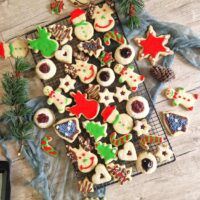 O selectie de biscuiti festivi pentru craciun , in forma sw mosi de zapada, braduti, stele, colorati si decorati cu glazura de zahar rosie si verde, unii umpluti cu dulceata altii cu ciocolata