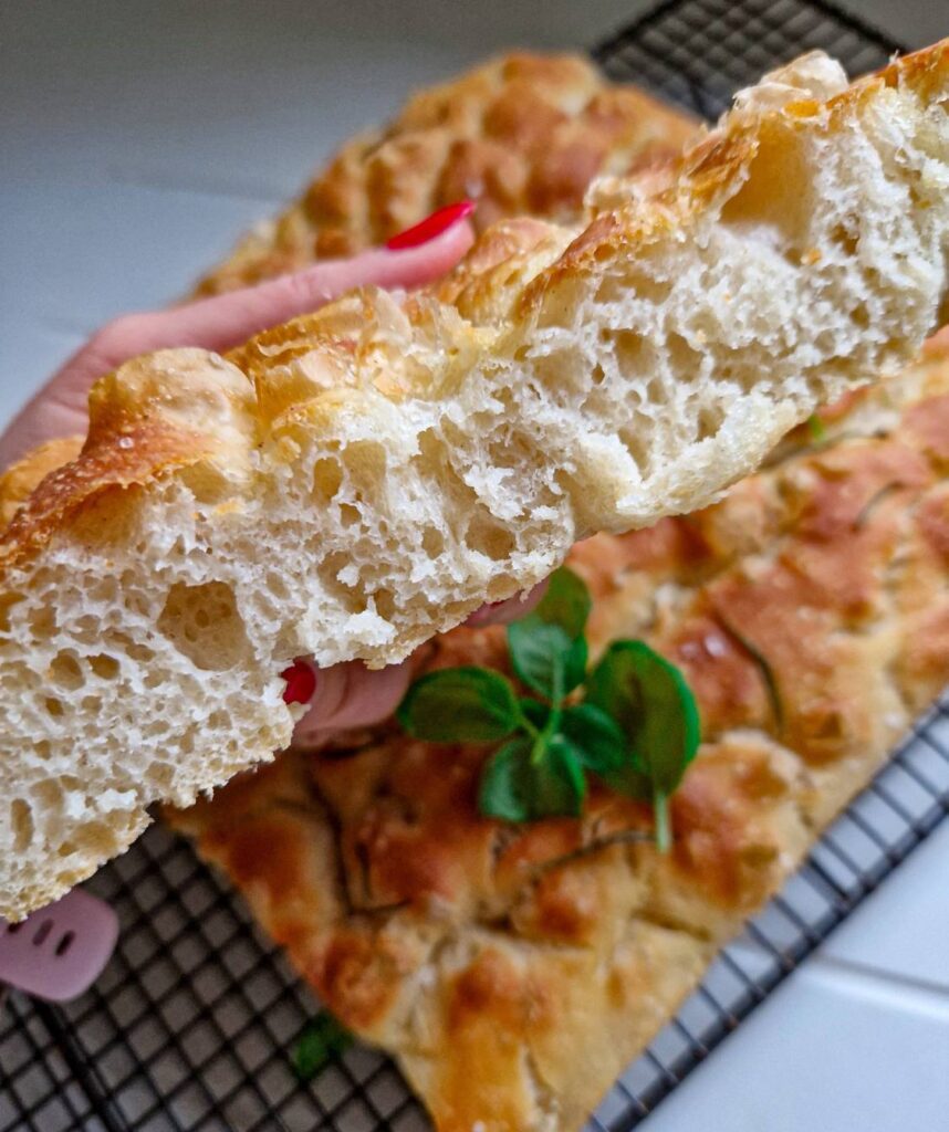 Focaccia cu fermentatie lenta, crusta crocanta si aurie, feliata, unde se vede cat de frumos a crescut, decorata cu sare de mare, rozmarin si busuioc