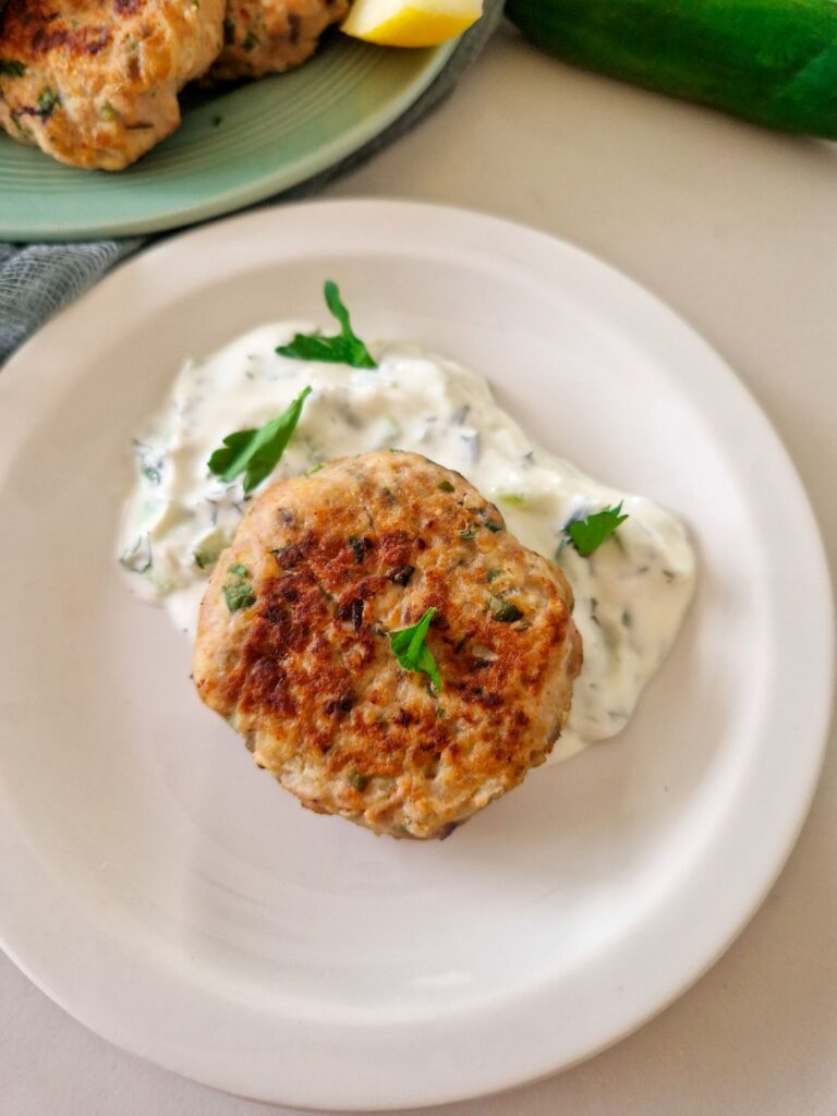 chifteluta de curcan pe o farfurie intr-un sos de iaurt si verdeturi, sos tzatziky