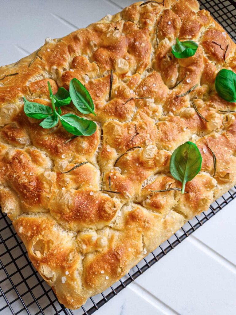 Focaccia cu fermentatie lenta, crusta crocanta si aurie, unde se vede cat de frumos a crescut, decorata cu sare de mare, rozmarin si busuioc