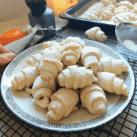 Cornulețe fragede cu untură și smântână, prezentate pe o farfurie, aproape, cu straturi delicate care se topesc în gură.