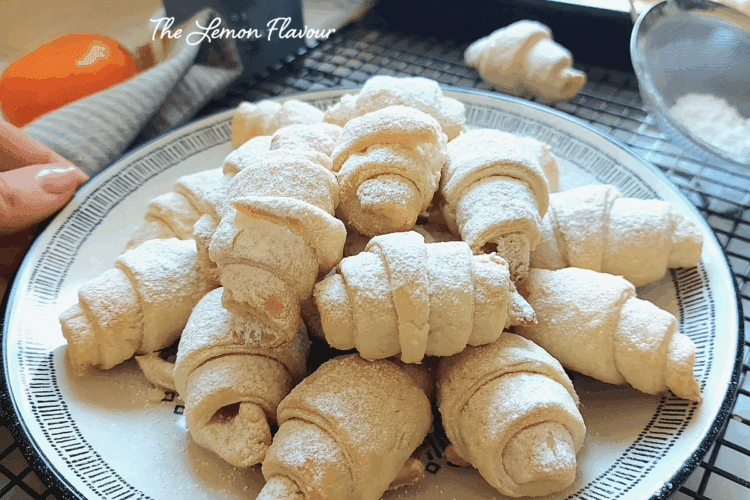 Cornulețe fragede cu untură și smântână, prezentate pe o farfurie, aproape, cu straturi delicate care se topesc în gură.