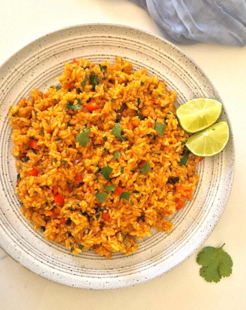 Orez mexican de post servit pe farfurie mare tip plateau, garnisit cu felii de lime și coriandru, fotografie de ansamblu