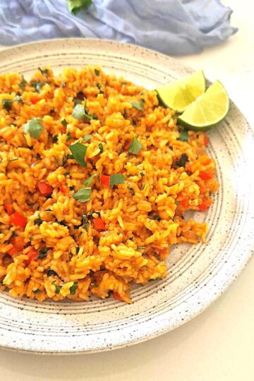 Orez mexican aromat de post, vedere de aproape pe farfurie tip plateau, decorat cu felii de lime și coriandru proaspăt