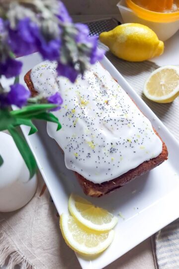 Chec umed cu lămâie și mac, întreg, proaspăt scos din tavă, cu coaja de lămâie vizibilă și culoare aurie apetisantă.