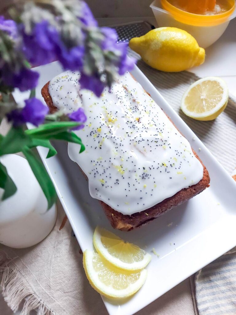 Chec umed cu lămâie și mac, întreg, proaspăt scos din tavă, cu coaja de lămâie vizibilă și culoare aurie apetisantă.