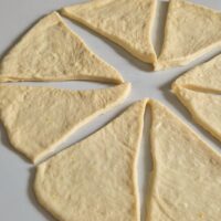 Aluat de post impartit in triunghiuri pentru cornuri pufoase pregatit sa fie umplute cu umplutura preferata