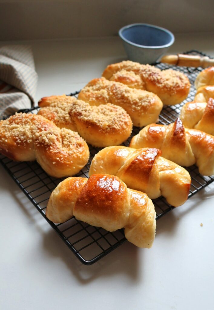 Cornuri si mucenici de post din aluat versatil de post peun gratar la racorit in spate se vede bolul cuemulsia si pensula, mucenicii suntdati cu nuca