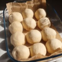 Chifle umplute cu brânză, formate și așezate în tavă înainte de dospire