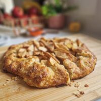 Tartă rustică cu mere, felie tăiată care arată aluatul fraged și umplutura de mere cu scorțișoară