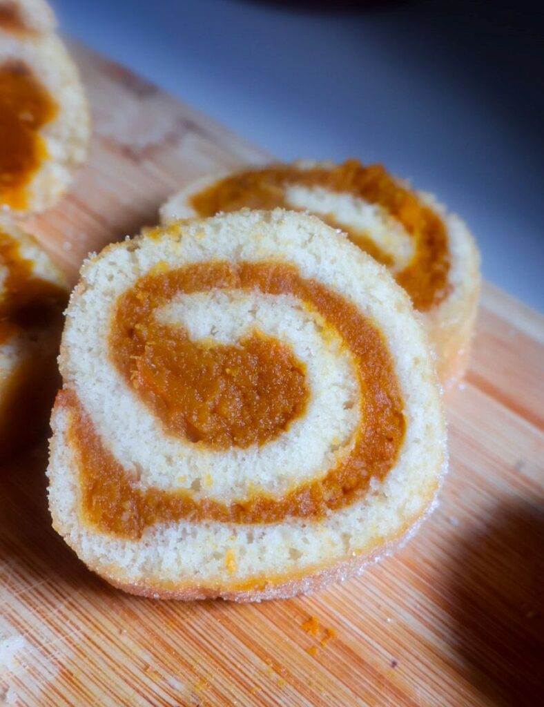 Felie de ruladă cu dovleac, cu blat deschis la culoare și umplutură de dovleac dispusă în spirală.